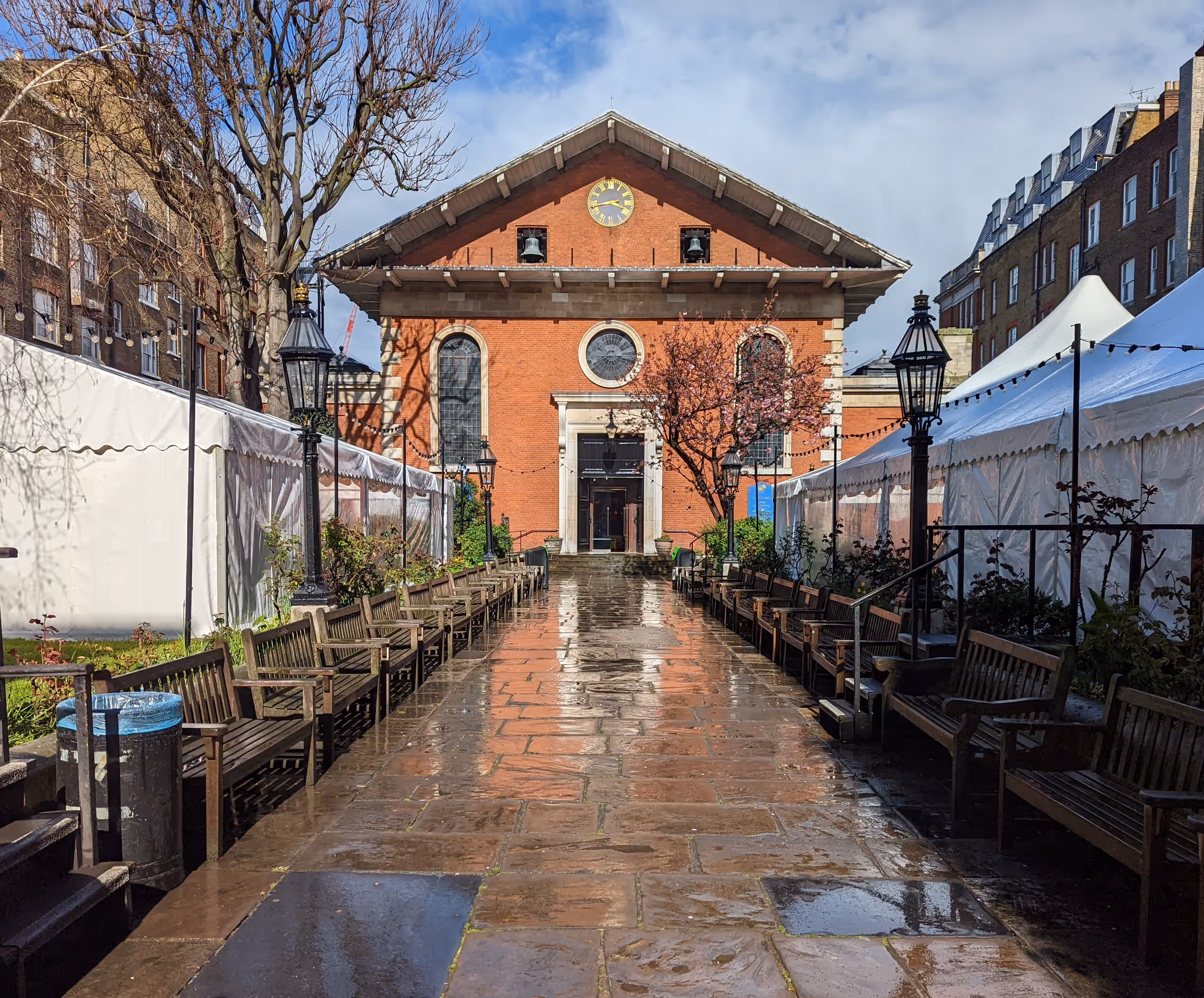 A view with the church entrance in the centre. On each side of the path there are large white marquees.