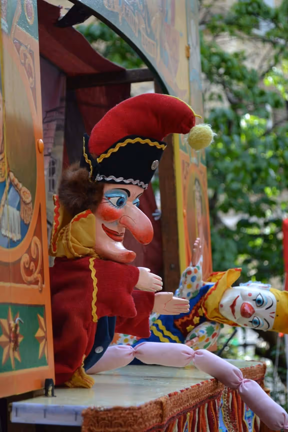 Mr Punch and a clown puppet on a brightly painted Punch and Judy booth at the May Fayre.