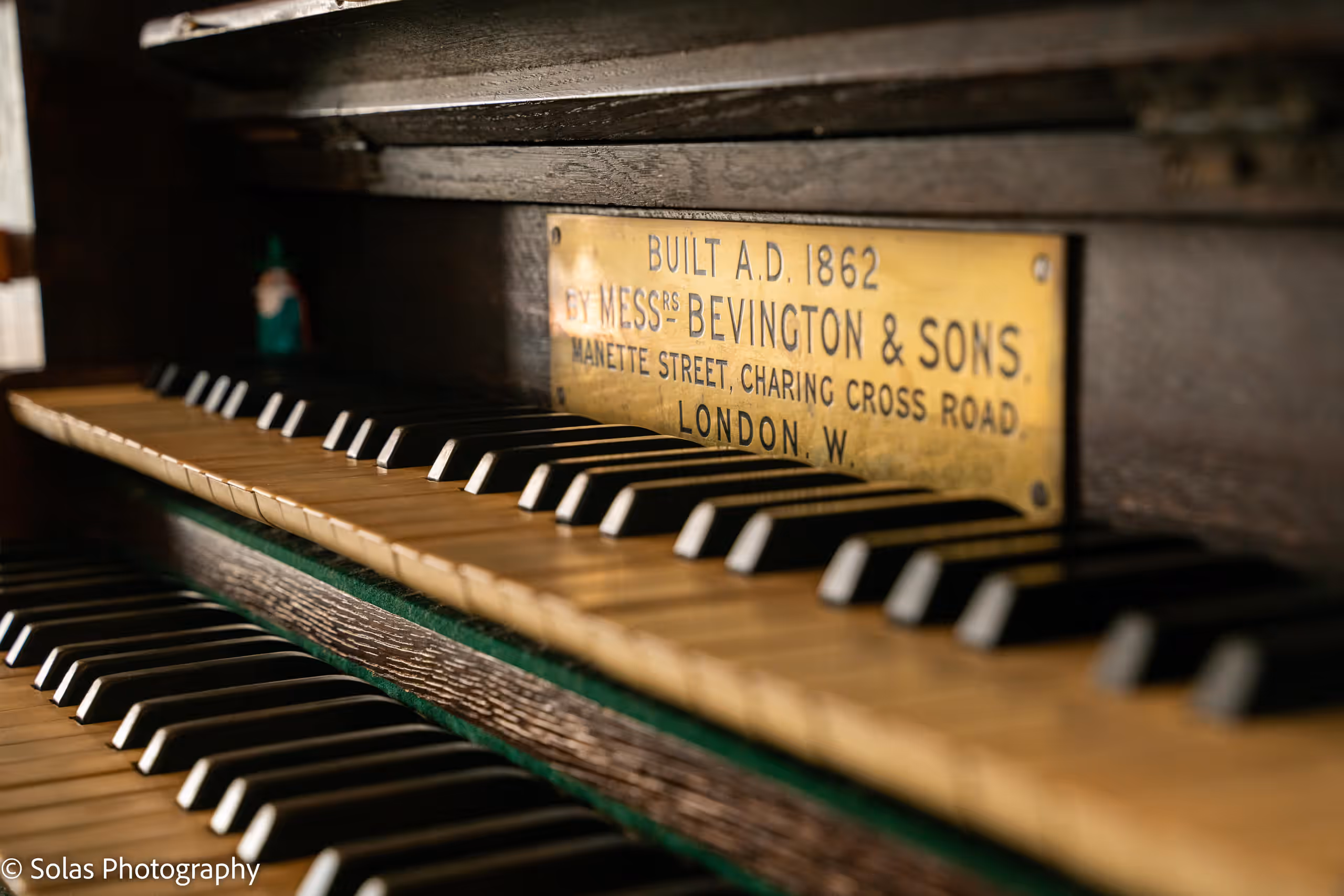 The organ keys below a brass maker's plate: Built A.D. 1862 by Messrs Bevington & Sons, London.