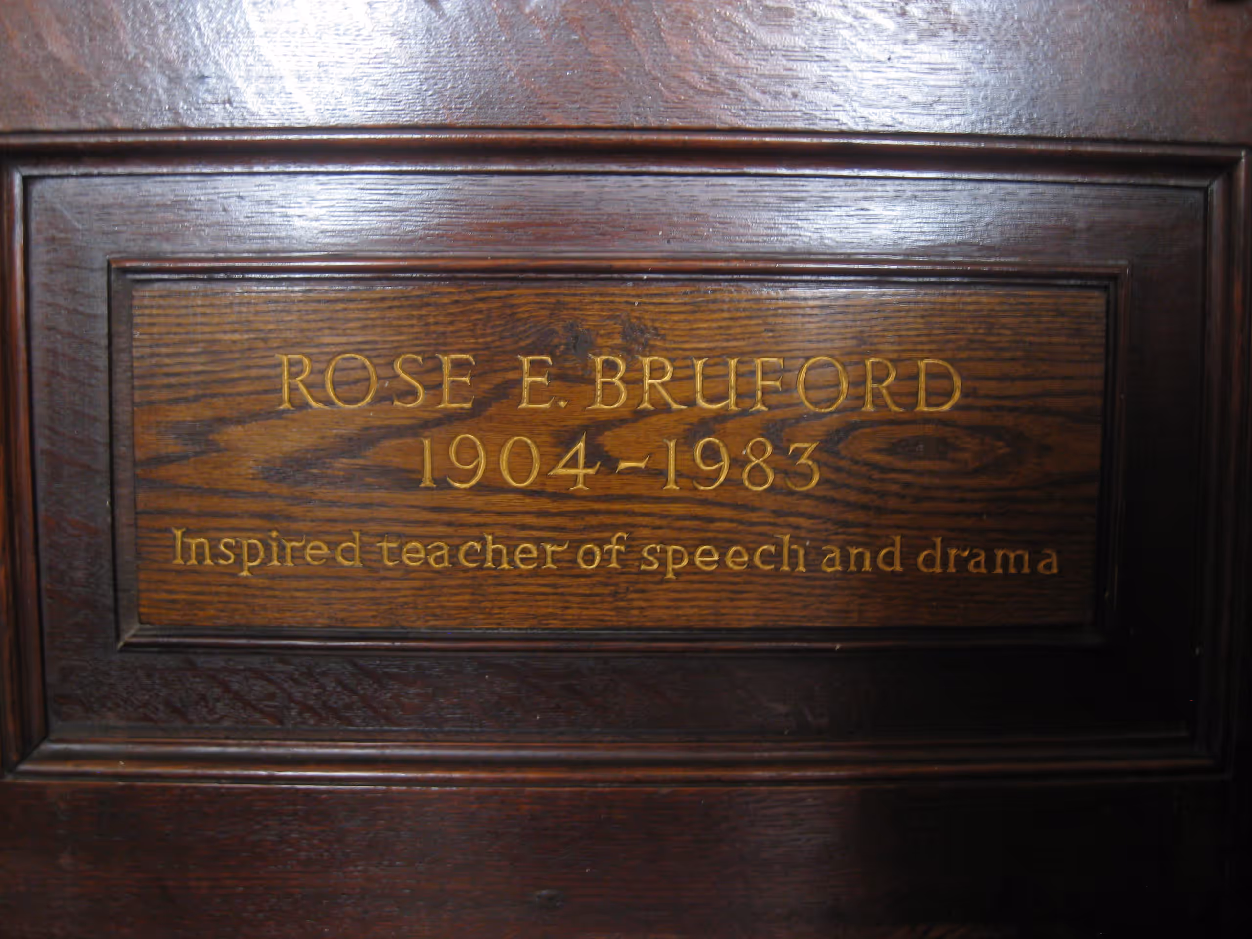 A wooden plaque in gold lettering: 'Rose E. Bruford, 1904–1983, Inspired teacher of speech and drama'.