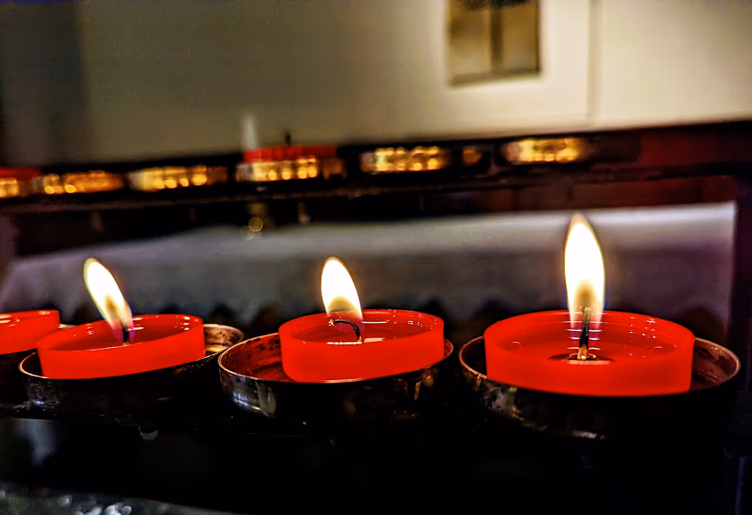 A row of lit red votive candles in the church.