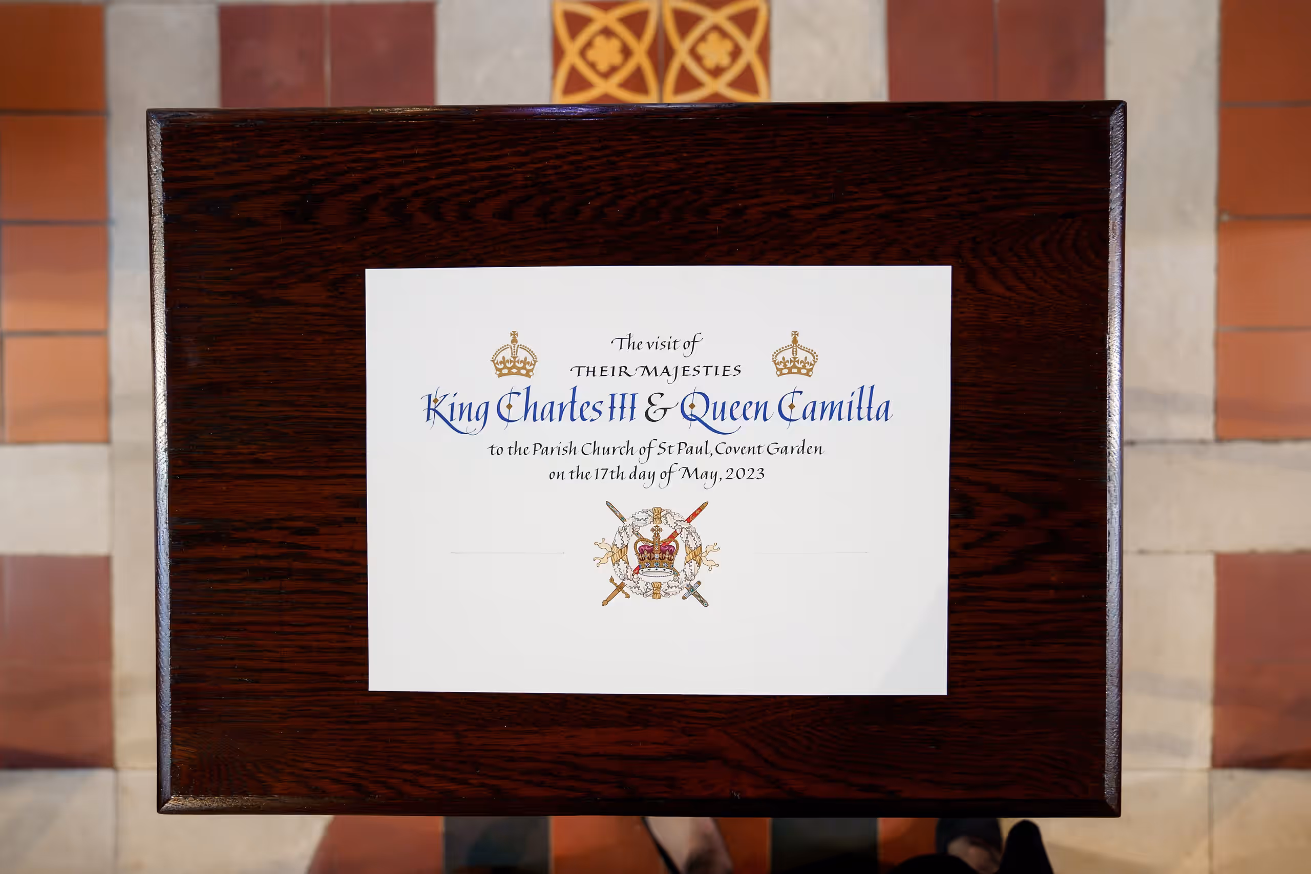A calligraphed card on a wooden board records the visit of King Charles III and Queen Camilla to St Paul's, Covent Garden, on 17 May 2023.